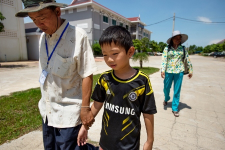 Luos Saekohn på väg över fängelsegården tillsammans med sonen för att besöka Yorm Bopha i fängelset.