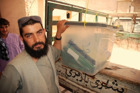 En av den afghanska valkommissionens medarbetare hämtar en fylld valurna.