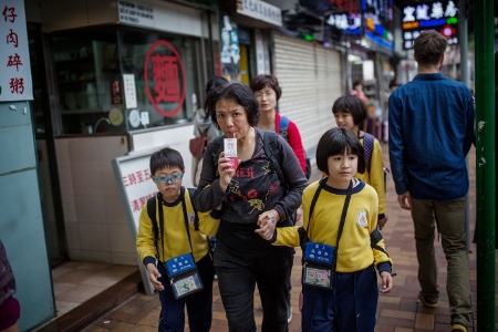 En kvinna följer två kinesiska barn från skolan i området Sheung Shui i Hongkong. 170 000 kinesiska barn föddes i Hongkong mellan 2001 och 2011, en populär metod för att ge dem tillgång till stadens suveräna utbildning.