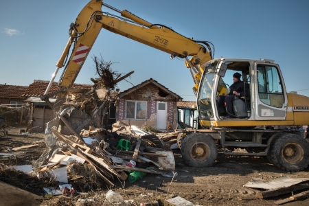 En grävskopa röjer undan resterna av tre förstörda hus i byn Voyvodinovo nära Plovdiv.