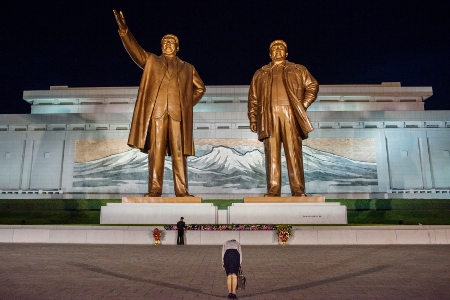 En kvinna bugar inför statyer på Kim Il-sung och sonen Kim Jong-il.
