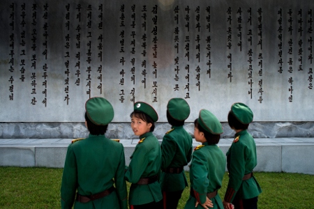 Unga kvinnliga soldater framför en vägg med namnen på stupade soldater.