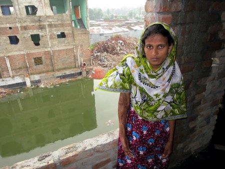 Hasina vid resterna av fabriksbyggnaden. Hon är en av 2 438 textilarbetare som överlevde då industribyggnaden Rana Plaza rasade samman i Dhaka-förorten Savar den 24 april 2013.