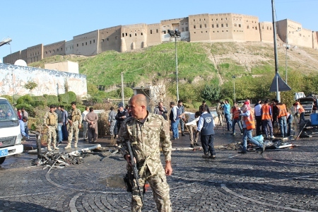 Räddningsarbetare städar upp efter ett bombattentat vid det lokala parlamentet i Erbil den 19 november. Sex personer miste sina liv.