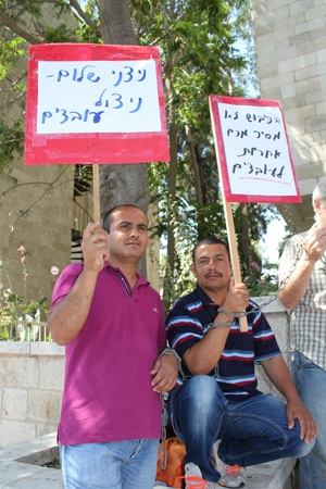 Palestinierna Ahmed Shaiyb och Hatam Abu Ziyada protester utanför Arbetsdomstolen i Jerusalem mot att de sparkades från sina arbetsplatser på israeliska bosättningar på Västbanken. 