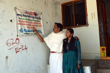 Den hinduiske prästen Shri Kumar Sharma visar tillsammans med sin dotter på den varning mot bortgifte av barn som sitter utanför hans kontor. Den som döms till att ha gift bort ett barn riskerar två års fängelse och dryga böter, är budskapet.