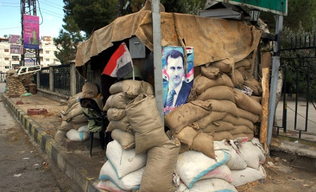 En vägspärr utanför Syriens huvudstad Damaskus med president Bashar al-Assads porträtt.