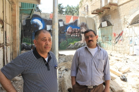 Hisham Sharabaty, fältarbetare för den palestinska människorättsorganisationen Al-Haq (till vänster) och Mofeed al-Sharabati framför en separationsmur i Hebron.