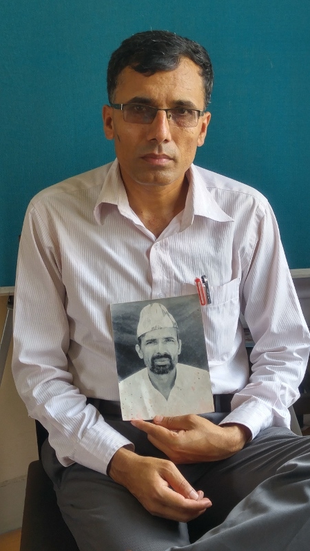 Suman Adhikari håller upp ett foto av sin far. Han är ordförande för Nepals gemensamma plattform för konfliktens offer.
