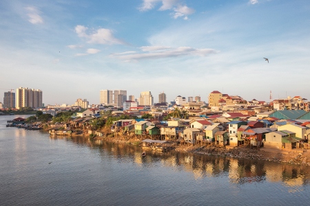 Kåkstäder vid Mekong-floden. I horisonten syns det nya Phnom Penh ta form. Investeringar av kinesiska företag ökar efterfrågan på mark och de fattiga områdena står som förlorare.