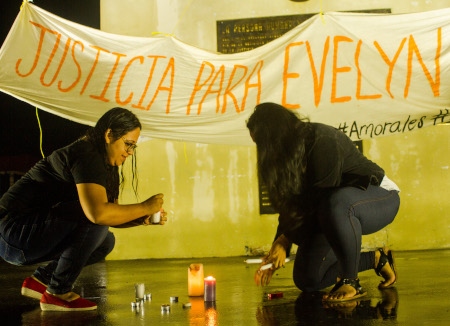 Två kvinnor tänder ljus i El Salvadors huvudstad i samband med protester mot att en ung kvinna dömts till 30 års fängelse efter att ha anklagats för att ha genomgått en abort.