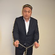 Omar Bekali har med sig en kopia av den 7 kilo tunga kedja han tvingades bära dygnet runt i lägret. Efter att ha blivit frisläppt hade han i början svårt att gå.