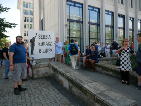Domaren Łukasz Biliński, som hittills ansvarat för rättegången, ska inom kort mot sin vilja omplaceras till avdelningen för familjerätt och demonstrationen utanför domstolen har anordnats i protest mot beslutet.