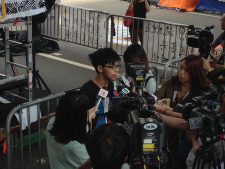 Joshua Wong håller presskonferens under Paraplyrörelsens protester 2014. Då var fokus krav på ökad demokrati i Hongkong. Den 29 oktober 2019 förbjöd myndigheterna Joshua Wong att ställa upp som kandidat i ett lokalval.