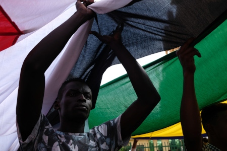 En demonstrant håller upp Sudans gamla och nya flagga.