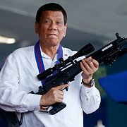 President Rodrigo Duterte håller upp ett gevär vid ett besök på Camp Crame 19 april 2018. Dutertes uppmaningar till krig mot narkotikan har skördat många människoliv sedan 2016.