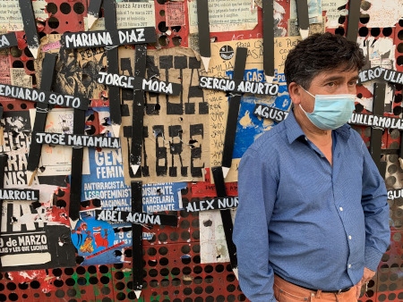 Anselmo Acuña, står framför ett provisoriskt monument över de som har dött under protesterna i Chile. Han står bredvid ett kors med sin sons namn.
