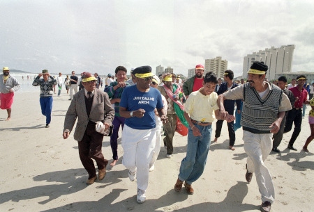 I september 1989 är denna strand i Sydafrika bara tillgänglig för vita och ärkebiskop Desmond Tutu (blå tröja i mitten) leder en joggingtur i protest.