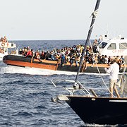 Italienska kustbevakningen  på väg in till hamnen på den lilla ön Lampedusa,  efter en räddningsinsats, sommaren 2023